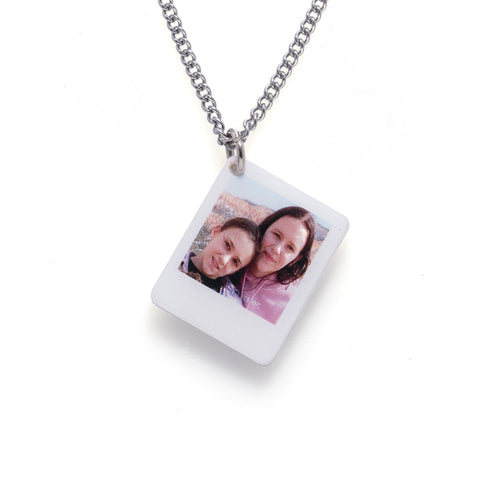 Two girls on a necklace, hanging gracefully.